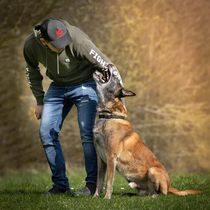 Handler in an IQ training hoodie rewarding his Malinois on the training field