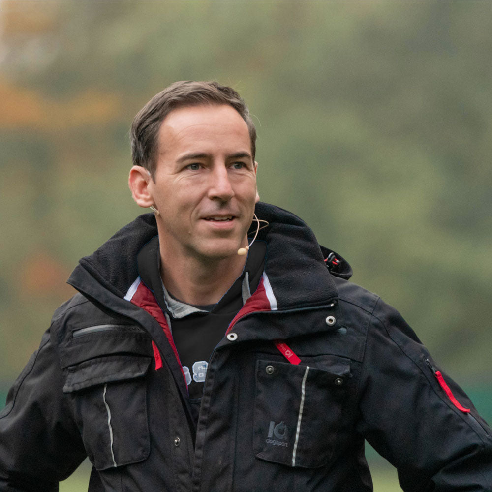 Hundeführer in schwarzer Multifunktionsjacke im IGP-Training
