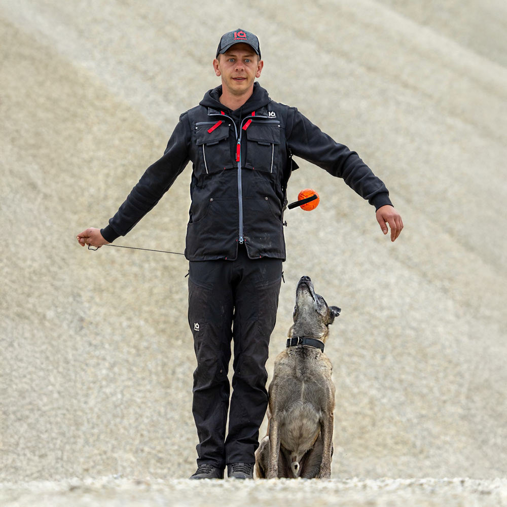 Handler releases a ball beside the vest while the dog watches