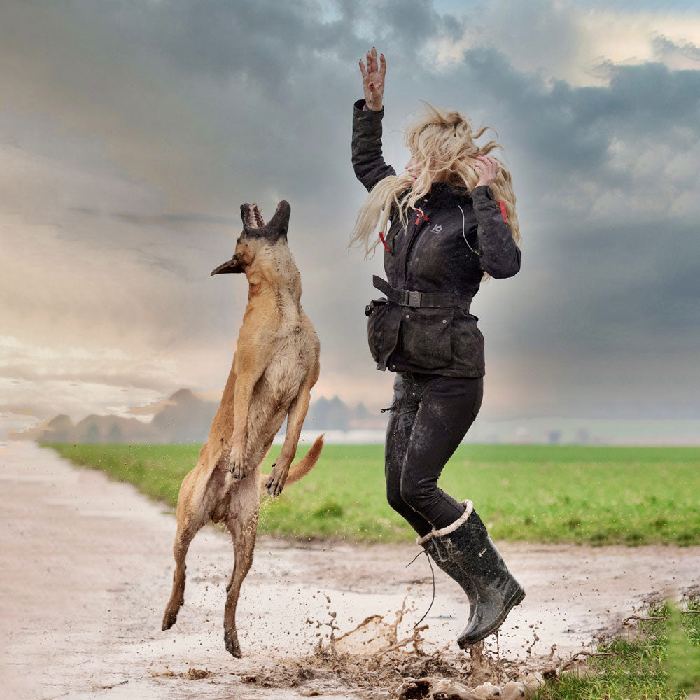 Handler in an IQ jacket training with a Malinois in wet weather