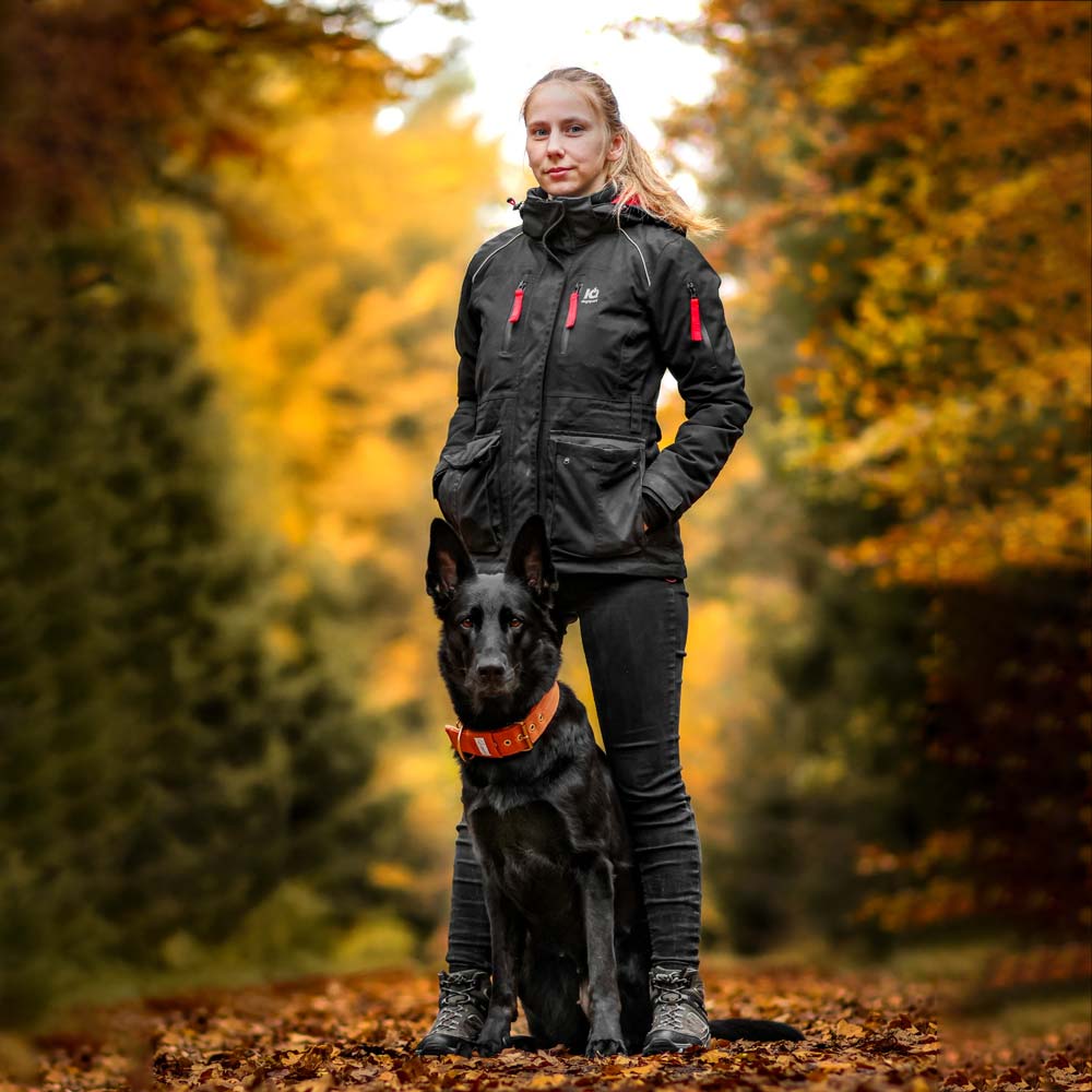 Hundeführerin mit Schäferhund in Multifunktionsjacke im Wald